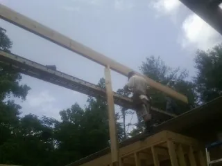 Carpenter setting a ridge beam over a new addition frame — Ice Dam Removal by Roofing Brothers in Preston Hollow