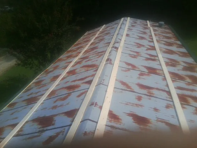 Rusted metal roof panels with new wood purlins before replacement — Storm Damage Roof Repair in Preston Hollow by Roofing Brothers