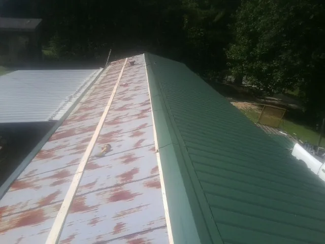 Old rusted panels beside newly installed green metal roofing — Wind Damage Roof Repair by Roofing Brothers in Preston Hollow
