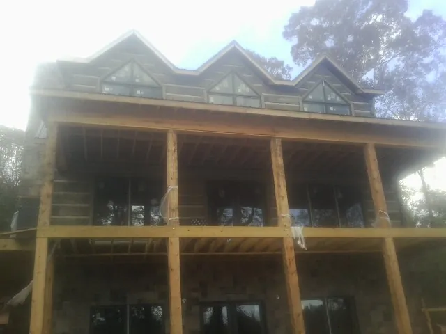 Dormers and porch framing on a large log home under construction — Roof Coating work by our crew in Preston Hollow