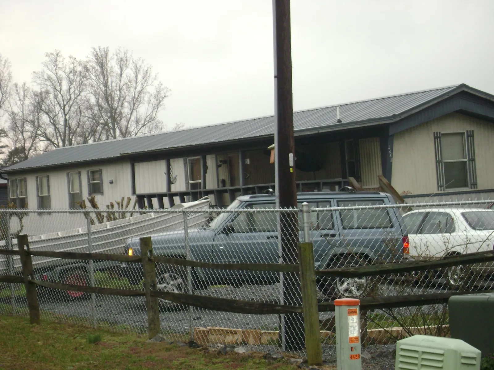 Dark metal roof on a long single story building behind a chain link fence in Preston Hollow