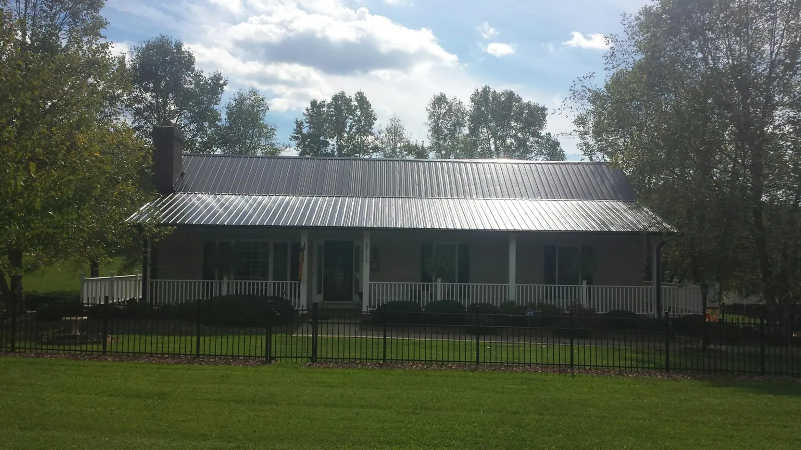 Gray metal roof on a brick ranch with a full width front porch — Gutter Guard Installation work by our crew in Preston Hollow