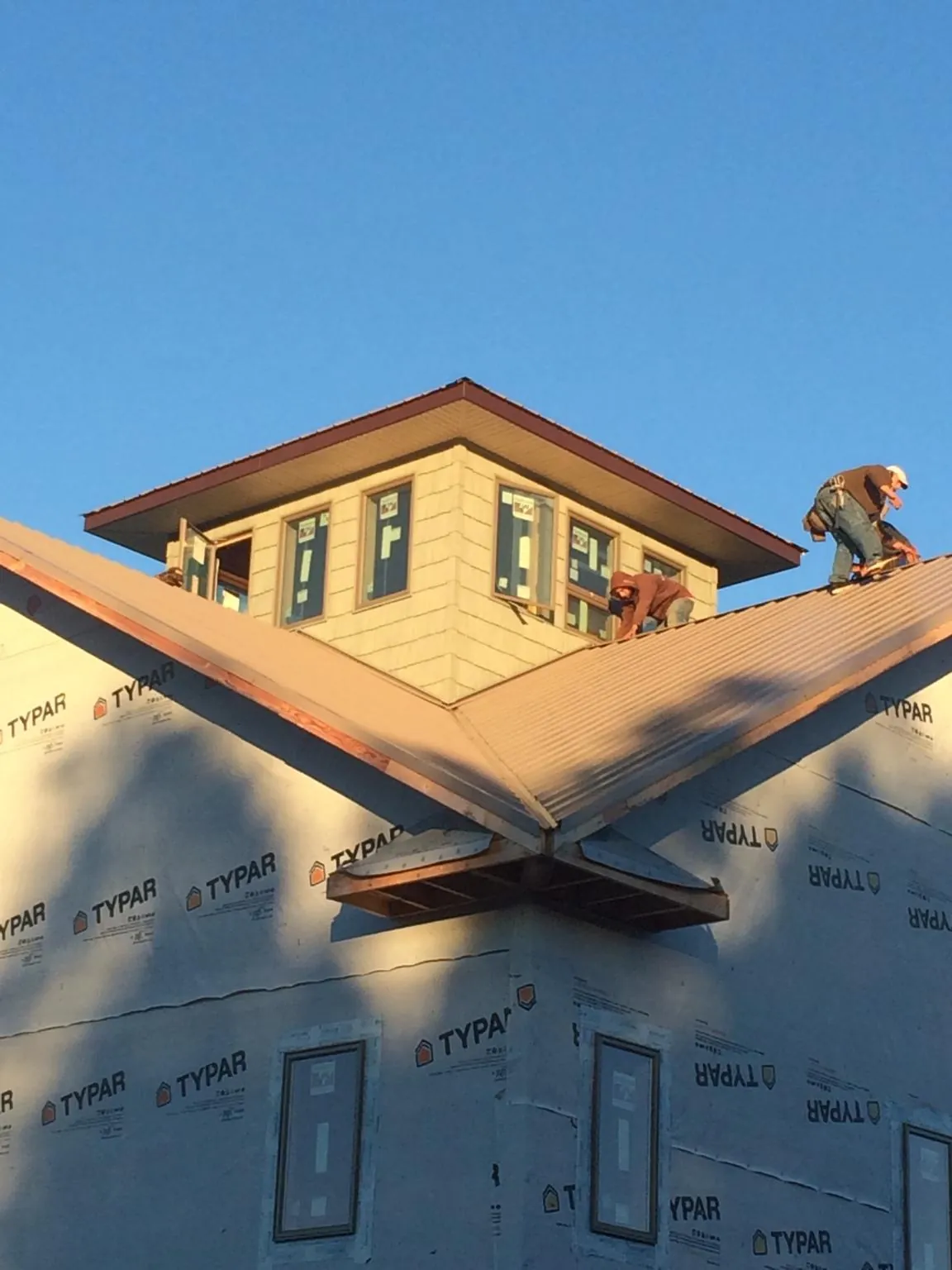 Roofers working around a rooftop cupola on a new metal roof at sunset — Roof Waterproofing in Preston Hollow by Roofing Brothers